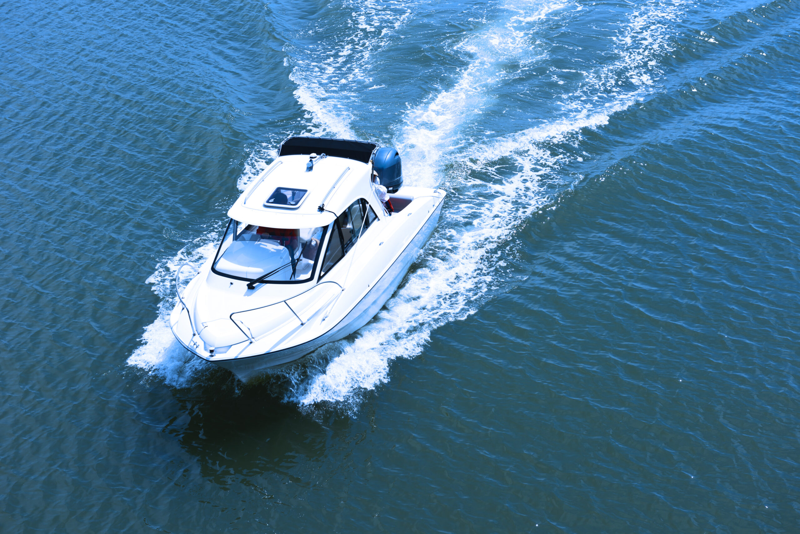 White boat making waves in ocean.